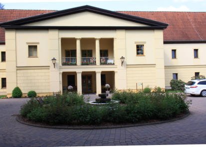 Eingangsfront mit Säulen, Balkon und Brunnen im Innenhof