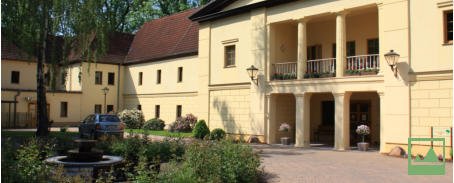 Weitläufige Parkanlage mit Rasenflächen, Bäumen und Sitzbänken vor dem Seniorenzentrum